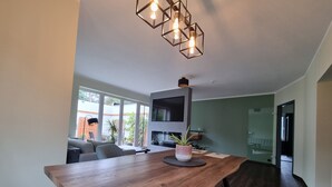 Een moderne eetruimte met een houten tafel, blauwe bekleden stoelen en een geometrische hanglamp.