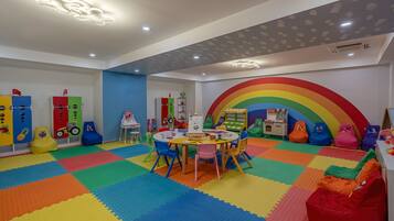 Ein Kinderspielzimmer mit bunten Matten, Sitzsäcken und Lernspielzeug.