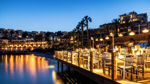 A waterfront dining area with tables and chairs, a wooden deck, and a view of the cityscape in the background. - Mirada Exclusive Bodrum (Bodrum)