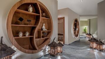 Un pasillo con estantes circulares de madera, una estatua de Buda y faroles tradicionales.