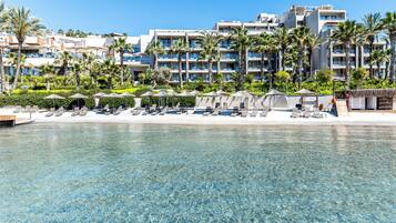 A resort with a clear pool, sun loungers, and a beach area.