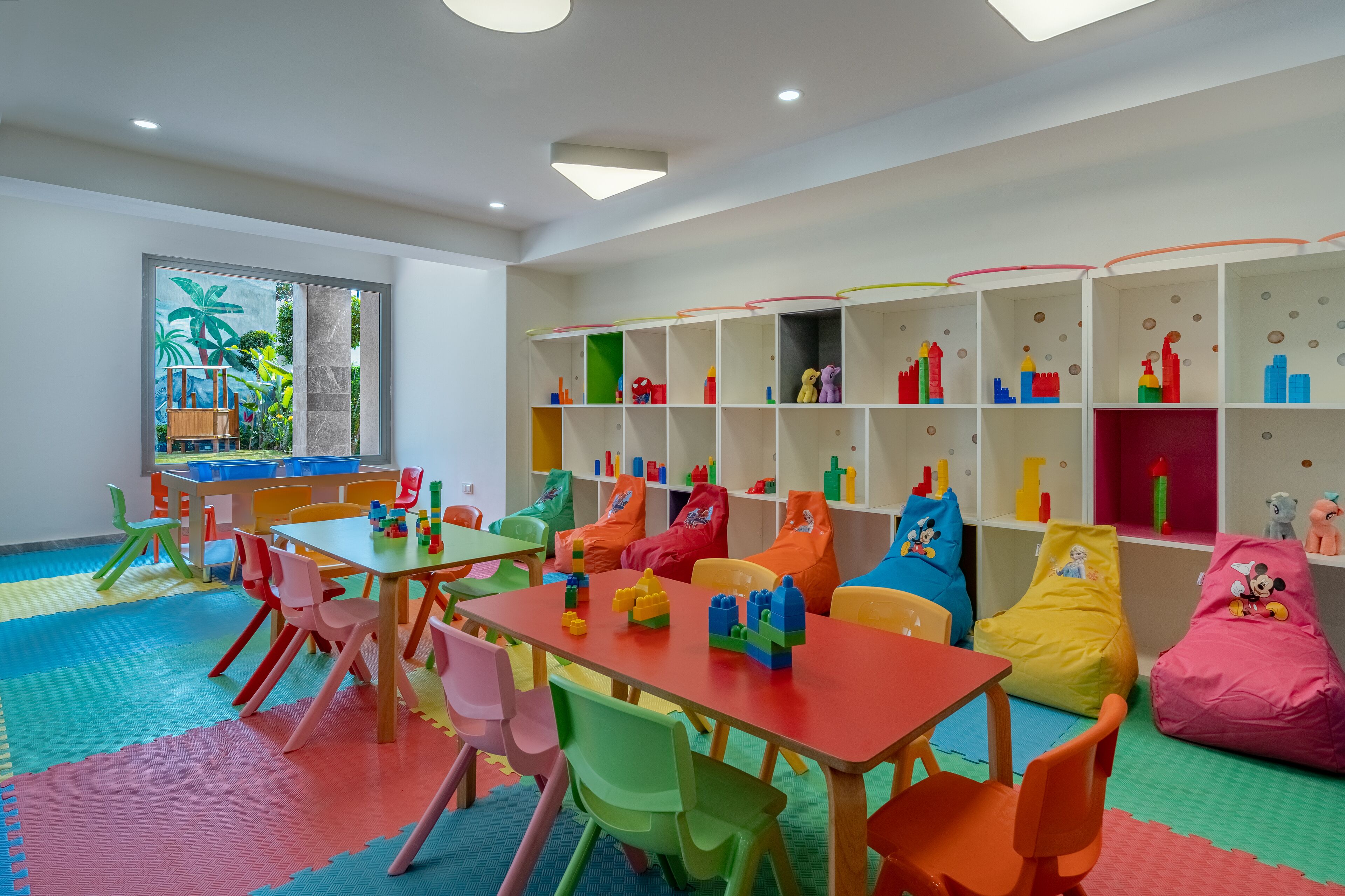 Ein Kinderzimmer mit farbigem Mobiliar und Regalen zur Aufbewahrung.