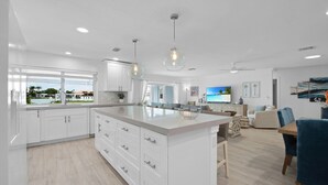 A modern kitchen with white cabinets, a large island, and pendant lighting. - CAPRI PARADISE!  Beautiful waterfront home.  Private heated pool and dock (Naples)