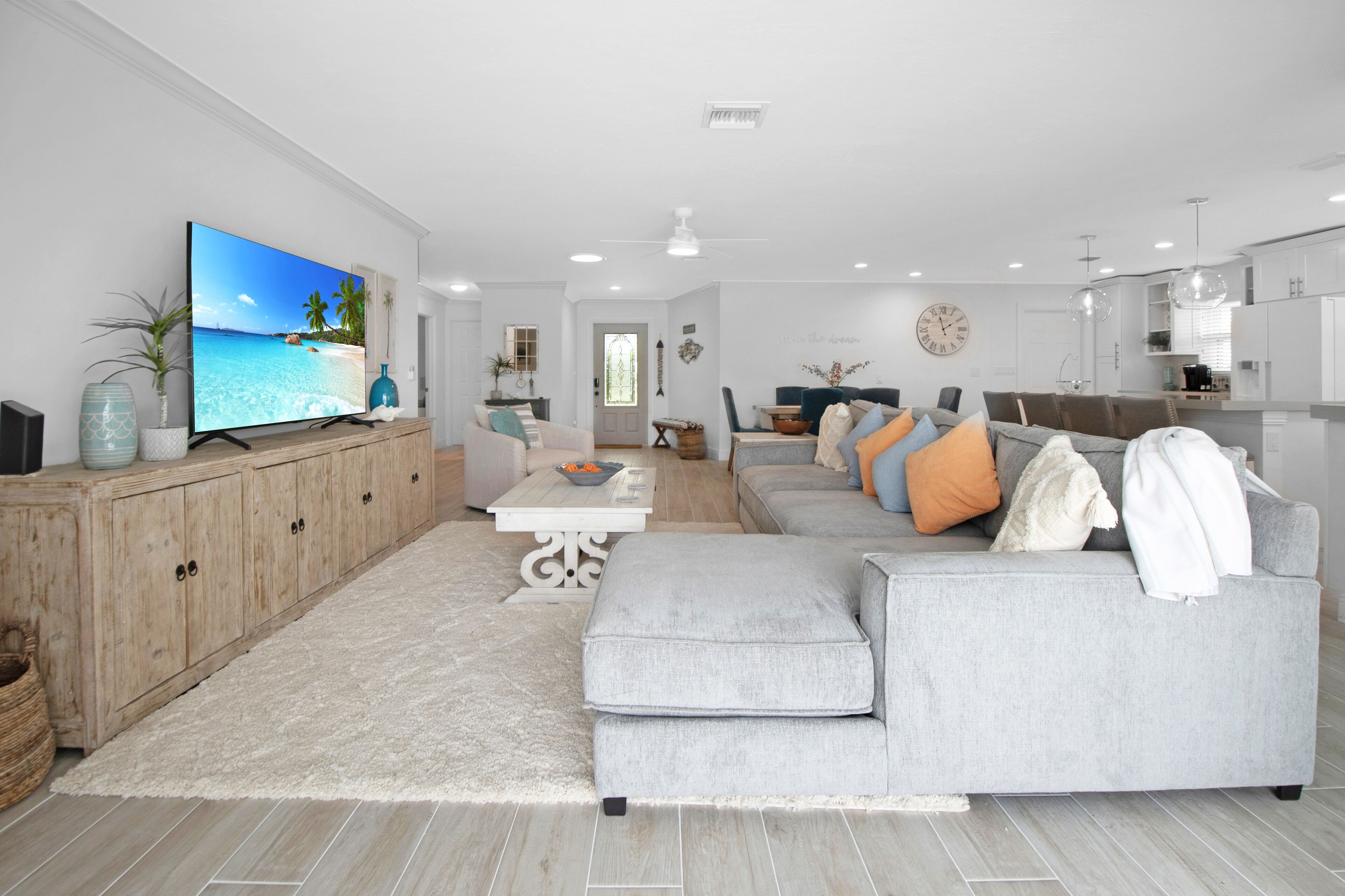 A modern living room with a large flat-screen TV, a grey sofa, and a wooden cabinet.
