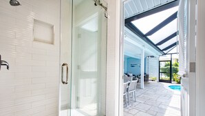 A modern bathroom with a glass shower enclosure, white tiled walls, and a stone accent. - CAPRI PARADISE!  Beautiful waterfront home.  Private heated pool and dock (Naples)