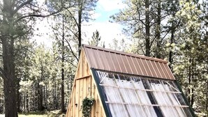 Une cabane en bois, dotée d’un toit en pente, entourée d’une forêt.