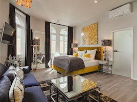Una habitación de hotel moderna con cama, sofá y una mesa de centro de vidrio.