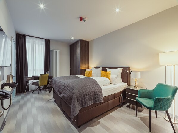 Una habitación de hotel con una cama grande, un escritorio, una silla y una lámpara.
