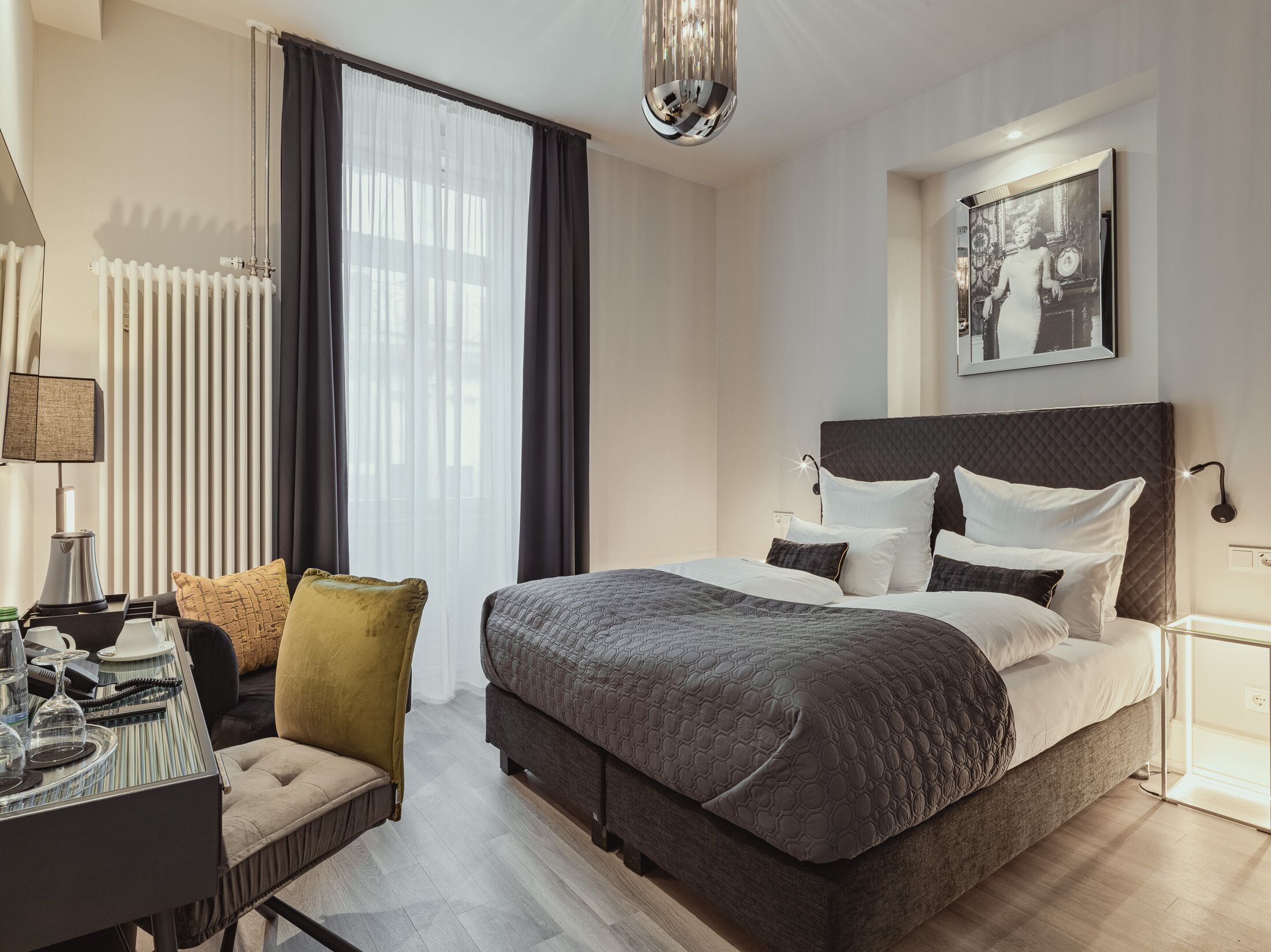 Una habitación de hotel moderna con una cama grande, un escritorio con silla y un área de comedor.