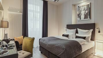 Una habitación de hotel moderna con una cama grande, un escritorio con silla y un área de comedor.