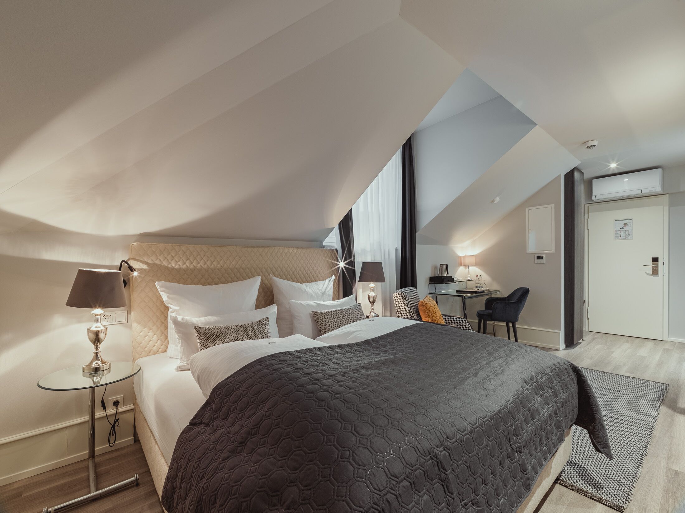 Ett modernt hotellrum med en stor säng, ett skrivbord och en stol.