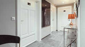 A hallway with white doors, numbered 26 and 28, and a glass table with a lamp. - BS Boutique Hotel (Heidelberg)