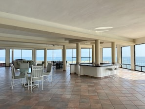 A spacious indoor area with large windows, a bar, and seating arrangements.
