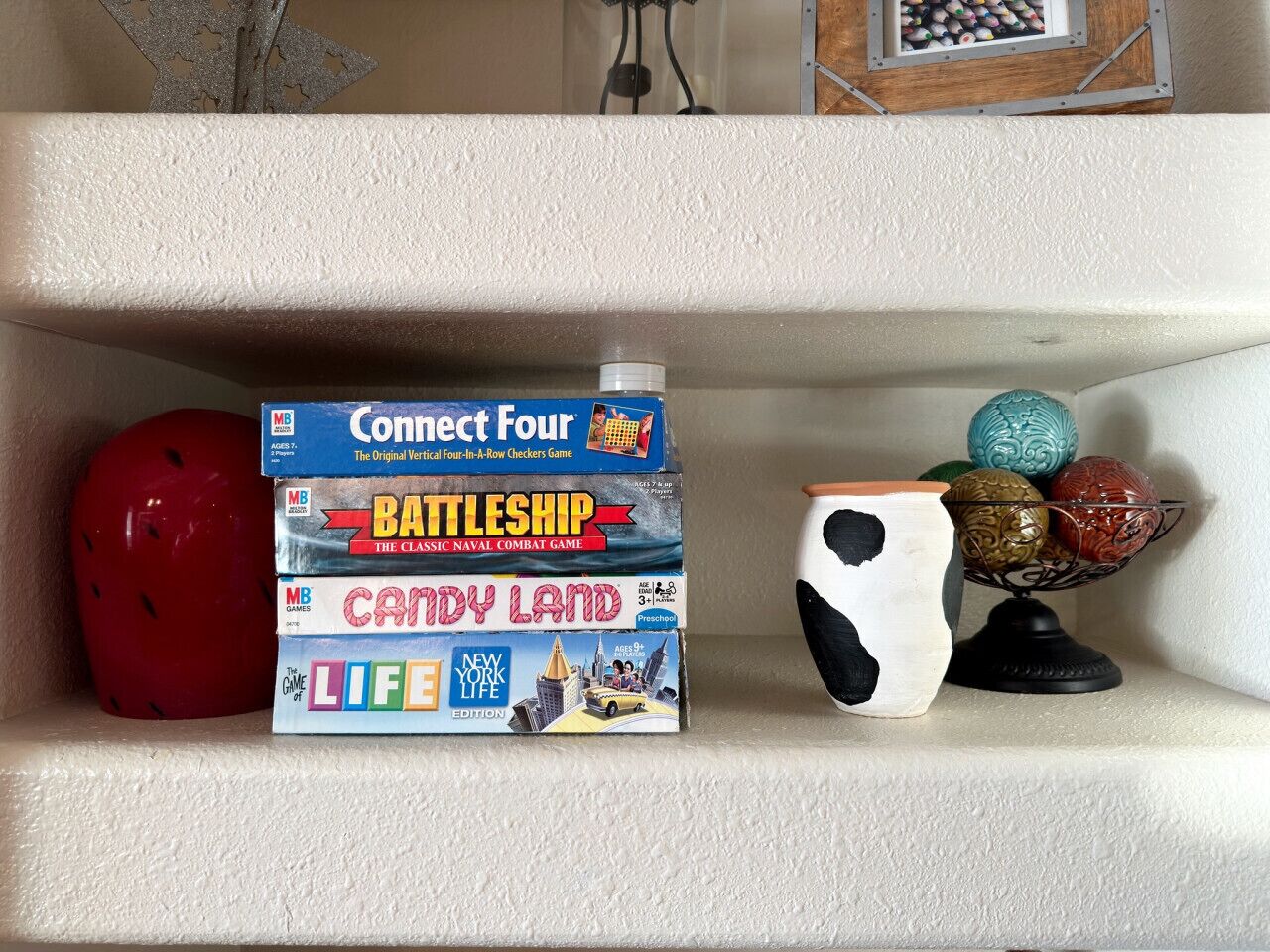 A shelf with board games including Connect Four, Battleship, Candy Land, and Life.