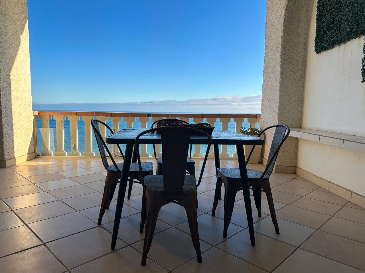 Une terrasse avec une table et des chaises, une vue sur la mer et un sol carrelé.