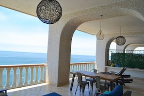 Enjoy the breathtaking sea views from this outdoor space with a table, chairs, and a hanging light fixture.