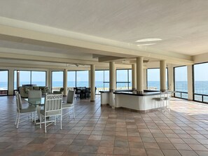 A spacious indoor area with large windows, a bar, and seating arrangements. - Rosarito Oceanfront Penthouse: Pool, Spa & Views in Costa Bella (Rosarito)