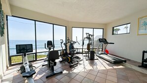 A gym with exercise equipment, large windows, and a view of the ocean. - Coastal luxury paradise (Rosarito)