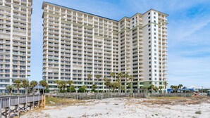 Un hotel de gran altura con varios balcones, vista al mar y un paseo marítimo de madera.