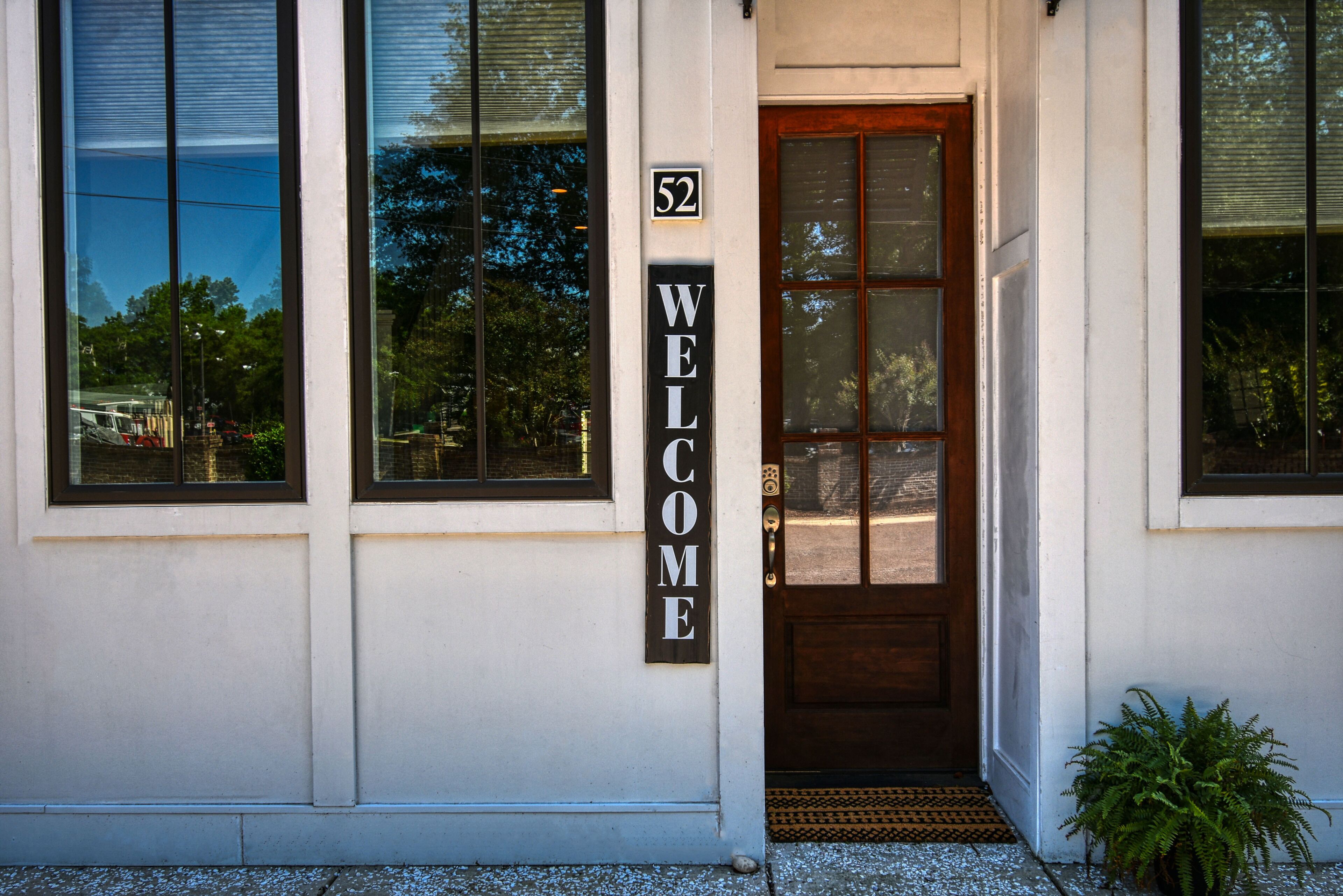 A building entrance with a 'WELCOME' sign and a door number '52'.