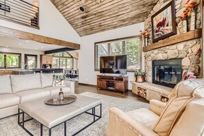 A spacious living room with a stone fireplace, a television, and a large window. - Point View | VIEWS | Golf Course | Hot Tub! (Breckenridge)