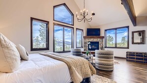 Un dormitorio amplio con una cama grande, varias ventanas, chimenea y un candelabro.