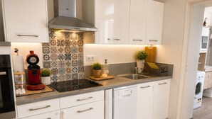A modern kitchen with white cabinetry, a stainless steel sink, a red coffee maker, and a dishwasher. - Luxury, peaceful, 3 bedroom family home (Saint-Quentin)