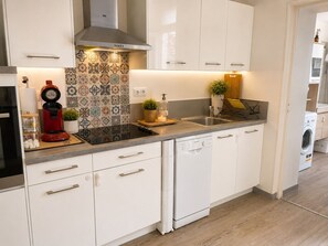 A modern kitchen with white cabinetry, a stainless steel sink, a red coffee maker, and a dishwasher. - Luxury, peaceful, 3 bedroom family home (Saint-Quentin)
