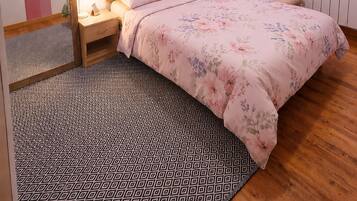 Un dormitorio con cama, mesita de noche, silla y espejo.