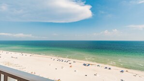 Une plage avec une eau turquoise et limpide, du sable blanc, ainsi que quelques parasols et chaises de plage.