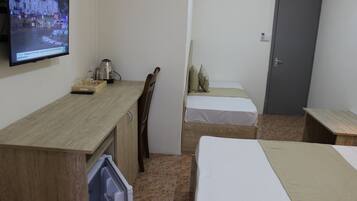 Una habitación pequeña y funcional con un escritorio de madera, una cama, una silla y un televisor montado en la pared.