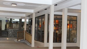 A spacious indoor area with a wooden staircase, glass doors, and a concrete floor. - Sikamifer Tourist Resort (Quatre Bornes)