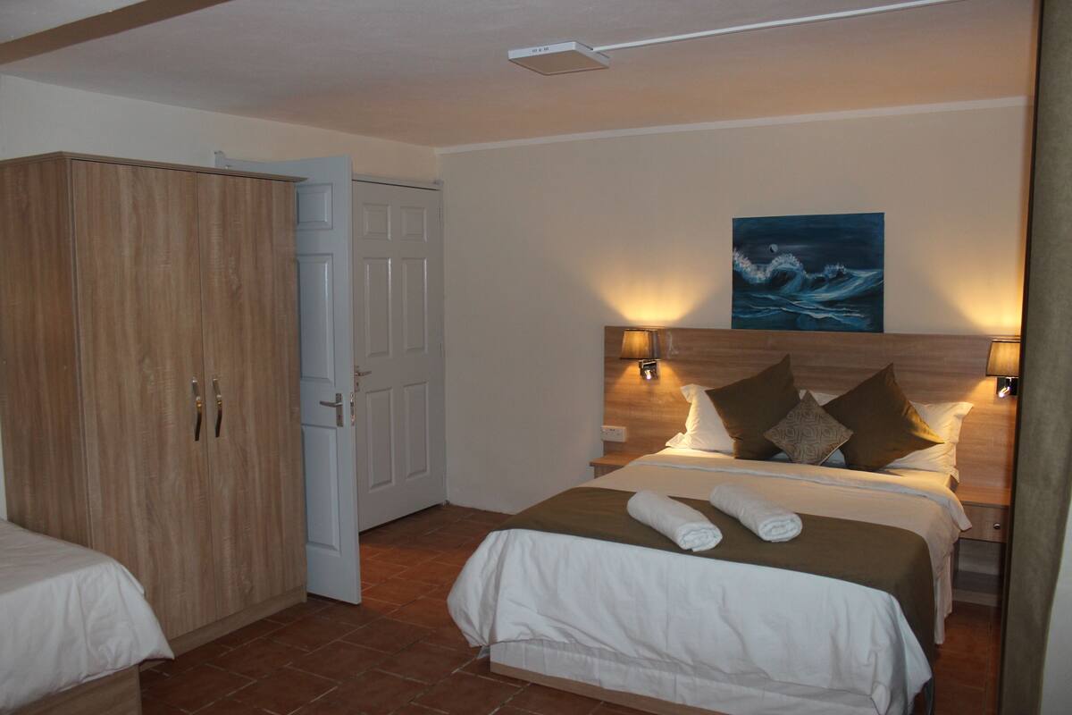 A bedroom with a bed, a wardrobe, a painting, and a nightstand.
