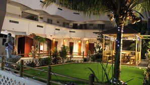 A multi-level hotel courtyard with a central lawn, palm trees, and a statue. - Sikamifer Tourist Resort (Quatre Bornes)