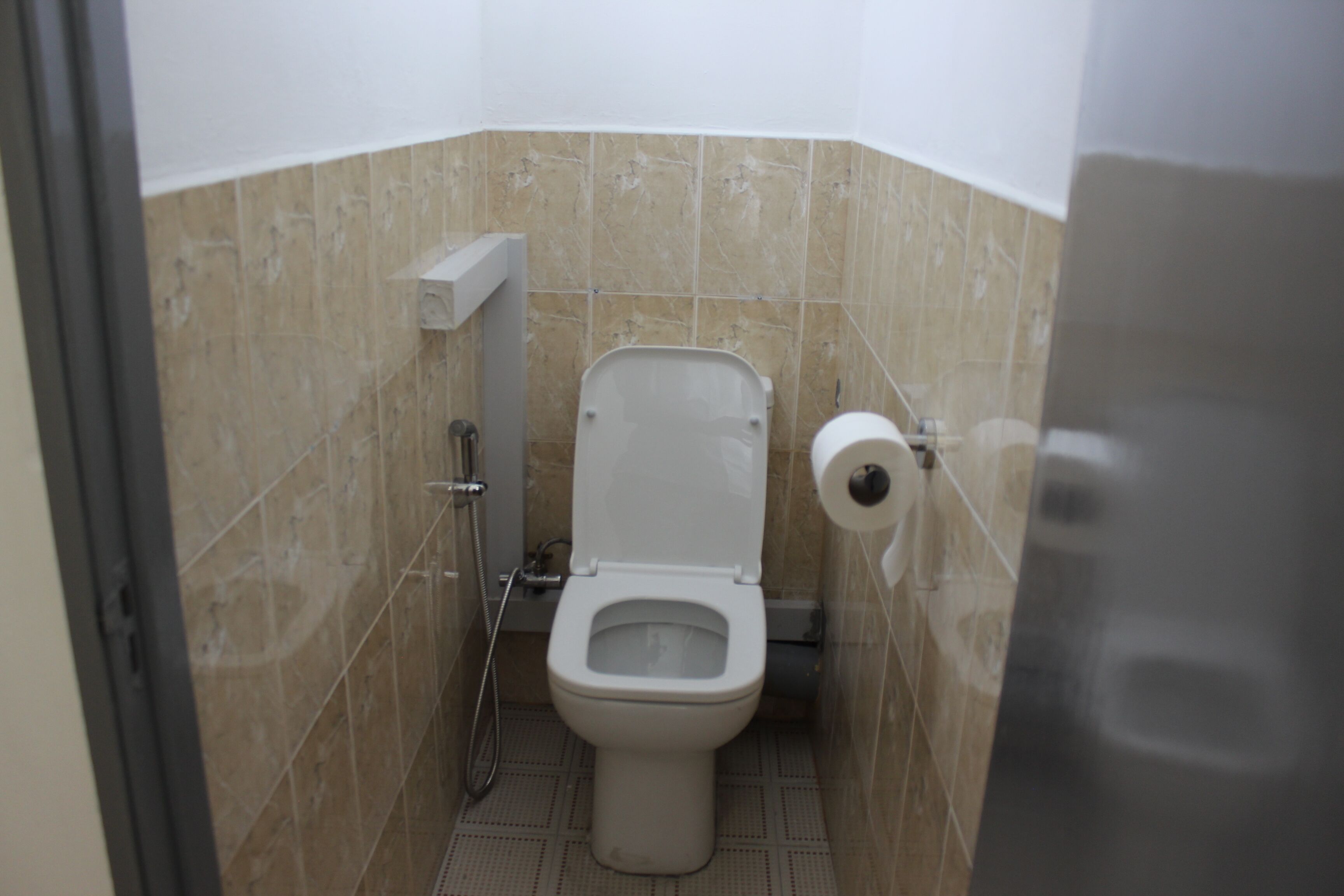 Un baño pequeño y funcional con inodoro, ducha y dispensador de papel higiénico.
