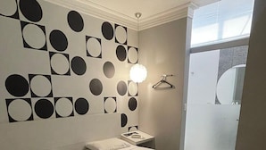 Et hotelværelse med to senge, en væg med geometrisk mønster, et natbord med lampe og udsigt ud