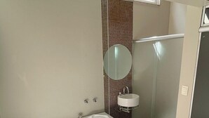 Et moderne badeværelse med et stort badekar, separat vask og et spejl.