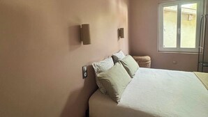 Camera da letto con un letto, due lampade a parete, una finestra e una ventola a soffitto.