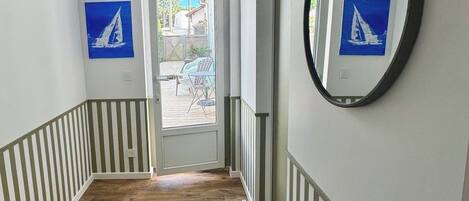 Um corredor com piso de madeira, um espelho na parede e duas imagens emolduradas.