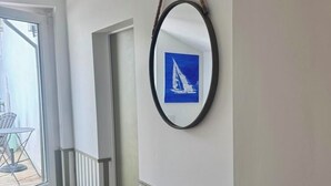 Un corridoio con pavimento in legno, ringhiera bianca e un quadro appeso al muro.