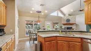 A spacious kitchen with granite countertops, wooden cabinets, and a large island.