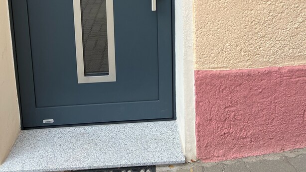Tumman sininen ovi, jossa on pystysuora lasipaneeli, hopeanvärinen kahva ja numeronäppäimistöllä varustettu lukko seinässä oven vieressä.