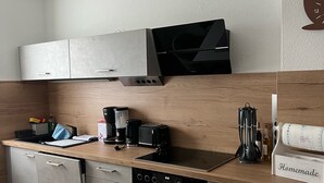 Moderni keittiö, jossa on mikroaaltouuni, leivänpaahdin ja kahvinkeitin työtasolla, liesi ja pesuallas.
