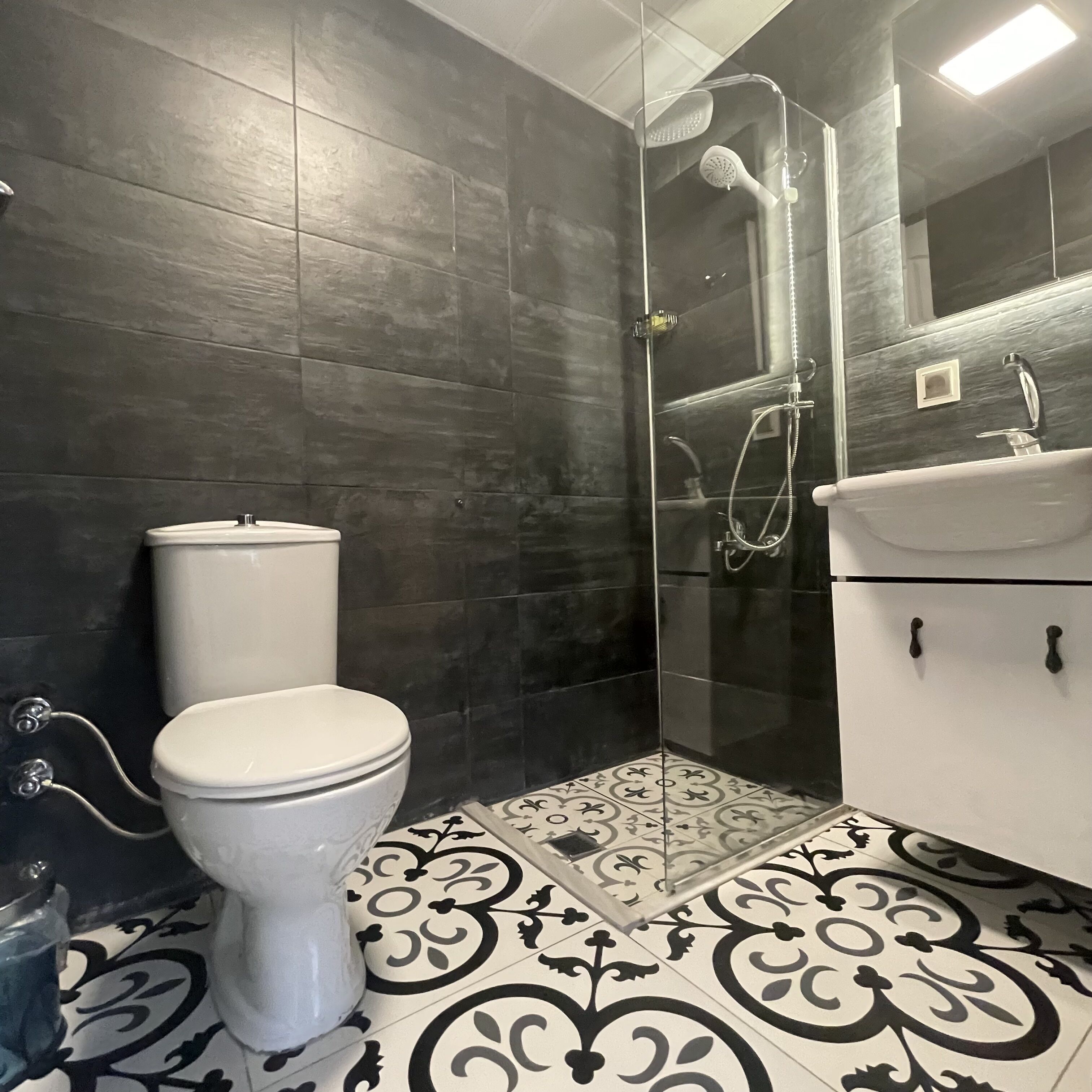 A bathroom with a toilet, a shower enclosure, and a sink.