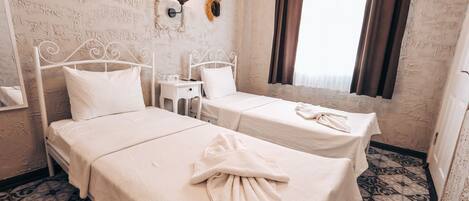 A room with two beds, a small table, and a wall-mounted lamp.