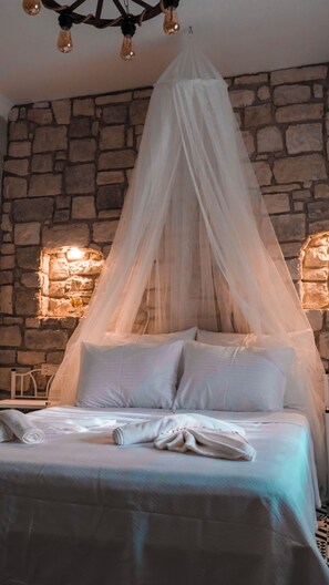 Un lit à baldaquin, un mur en pierre et un luminaire suspendu.