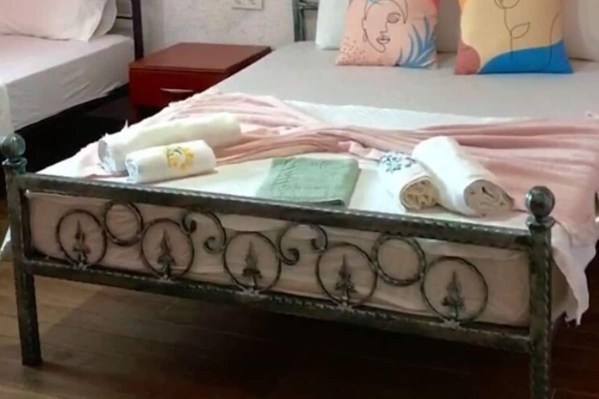 A bedroom with a bed, a bedside table, a wardrobe, and a wall-mounted shelf.