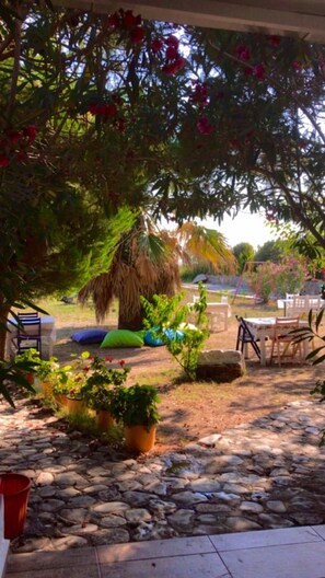 A garden area with a stone pathway, outdoor furniture, and potted plants. - Merve Bağ Evi Pansiyon (Bozcaada)