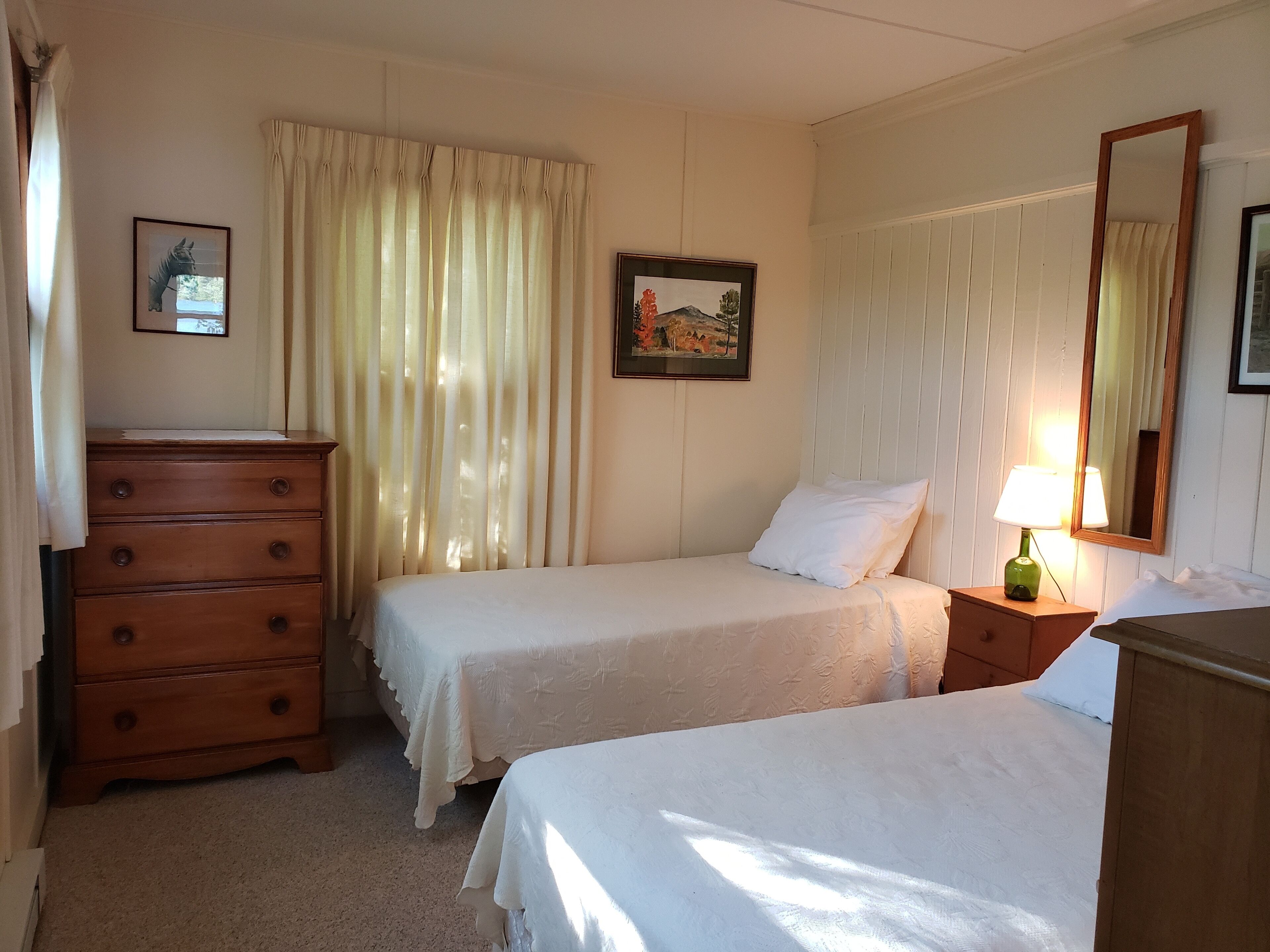 Ein Hotelzimmer mit zwei Betten, einem Schminktisch, einer Lampe und einem Bild an der Wand.