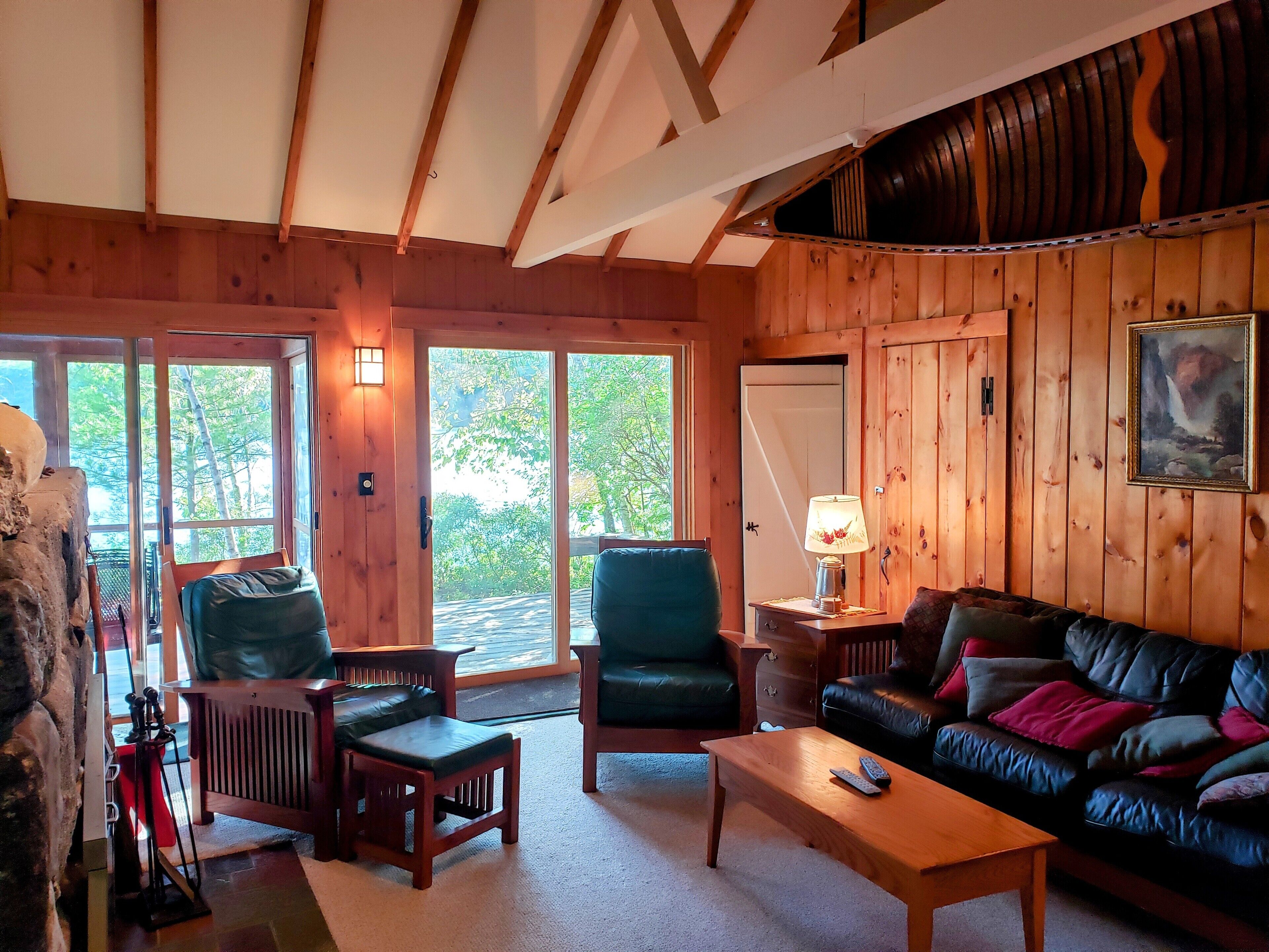 L’intérieur chaleureux d’un chalet avec des murs en bois, un canapé en cuir, une table basse en bois et une cheminée en pierre.
